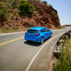 A blue 2024 Subaru Impreza Sport drives on a canyon road.